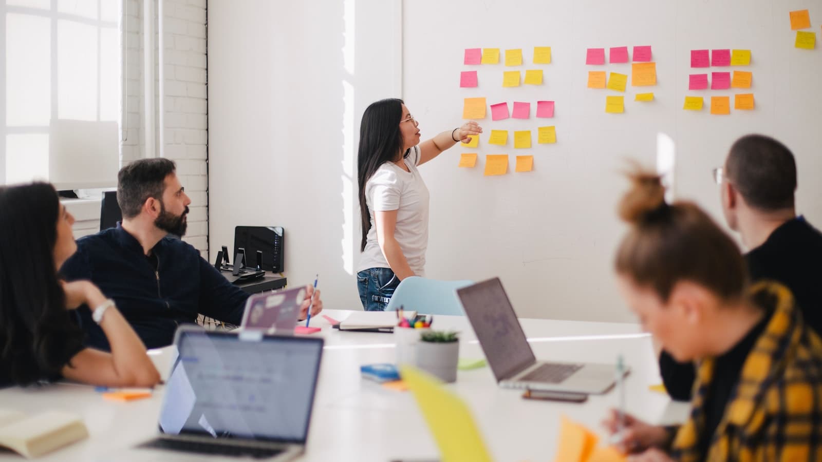 Team around a table reviewing notes on a wall